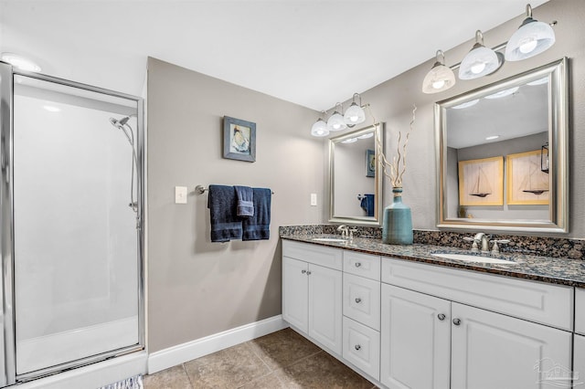 full bath with double vanity, a shower stall, baseboards, and a sink