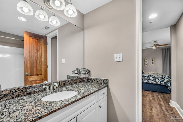 bathroom with visible vents, wood finished floors, baseboards, ceiling fan, and vanity