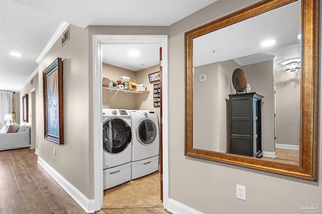 clothes washing area featuring baseboards, visible vents, washing machine and clothes dryer, laundry area, and ornamental molding