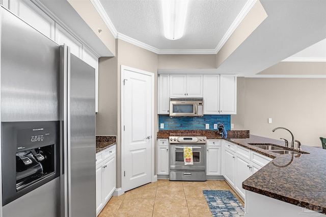 kitchen featuring a peninsula, a sink, stainless steel appliances, white cabinets, and crown molding