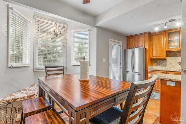 dining room with light tile patterned floors, rail lighting, a notable chandelier, and plenty of natural light