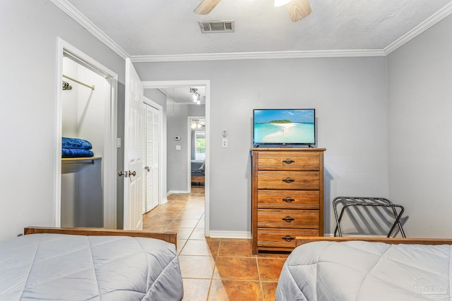 tiled bedroom with a closet, ceiling fan, and ornamental molding