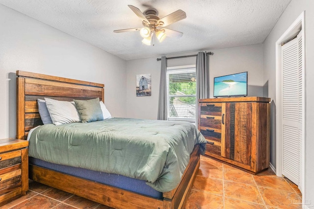 tiled bedroom with ceiling fan, a closet, and a textured ceiling