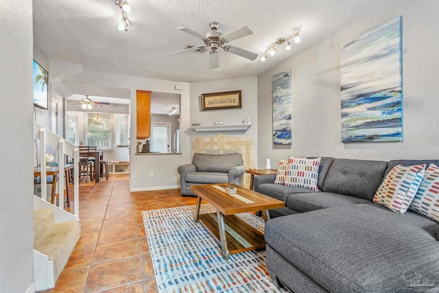 living room with a textured ceiling, ceiling fan, rail lighting, and light tile patterned floors