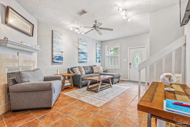 living room with ceiling fan, light tile patterned flooring, a textured ceiling, and track lighting