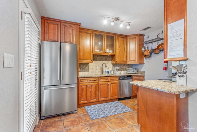 kitchen with backsplash, sink, rail lighting, light tile patterned floors, and stainless steel appliances