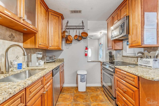 kitchen featuring appliances with stainless steel finishes, decorative backsplash, light tile patterned floors, and sink