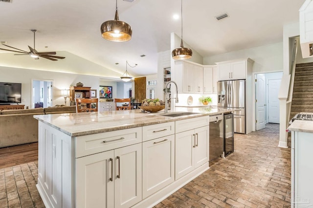 kitchen with appliances with stainless steel finishes, pendant lighting, white cabinetry, an island with sink, and sink