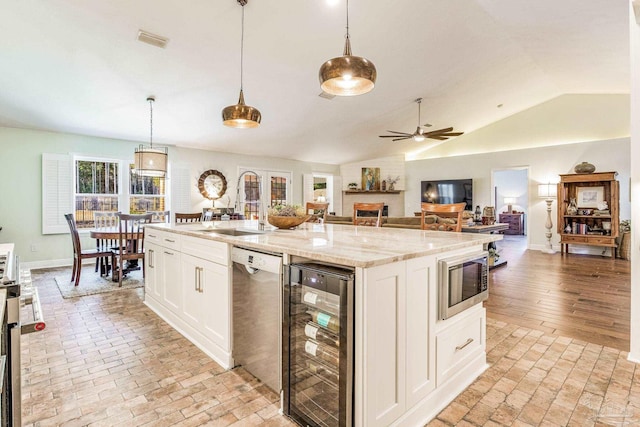 kitchen featuring wine cooler, hanging light fixtures, an island with sink, stainless steel appliances, and white cabinets