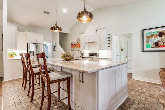 kitchen featuring pendant lighting, white cabinetry, stove, light stone countertops, and custom range hood