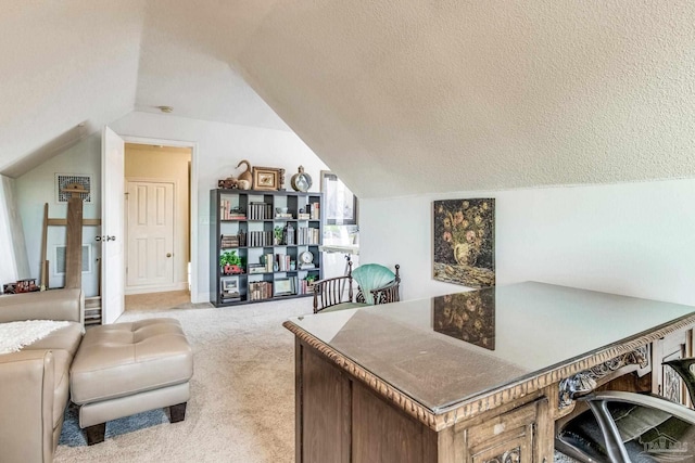 carpeted home office featuring vaulted ceiling and a textured ceiling