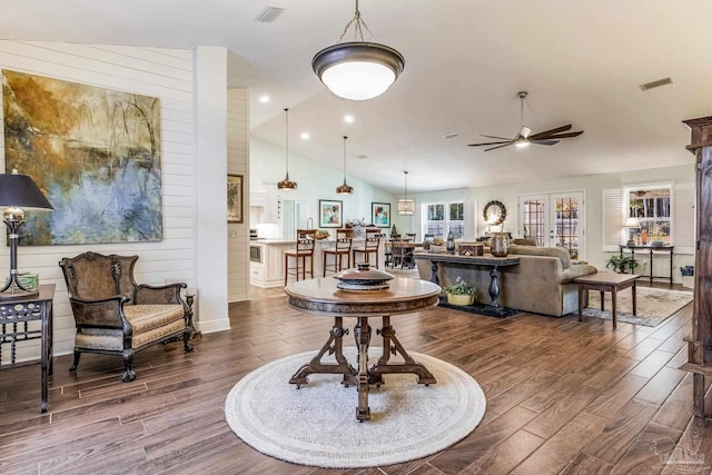 living room featuring hardwood / wood-style floors, vaulted ceiling, wooden walls, and ceiling fan