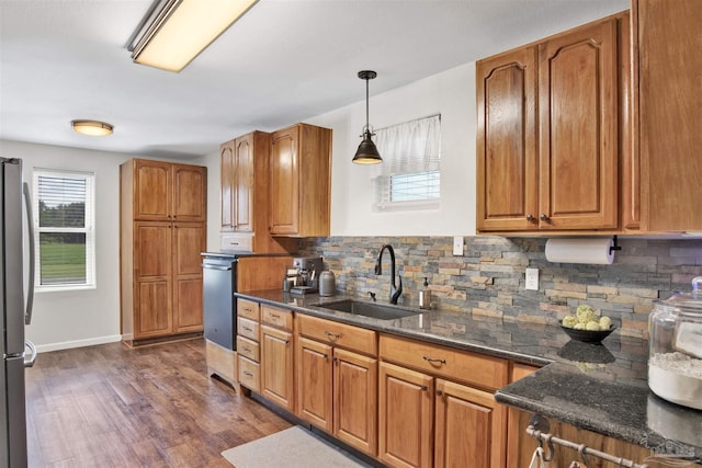 kitchen featuring dark wood-type flooring, sink, tasteful backsplash, decorative light fixtures, and dark stone counters