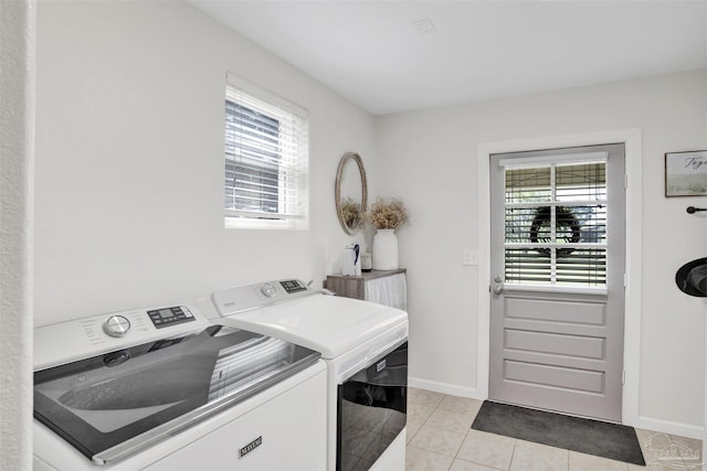 clothes washing area with a wealth of natural light, washer and clothes dryer, and light tile patterned floors