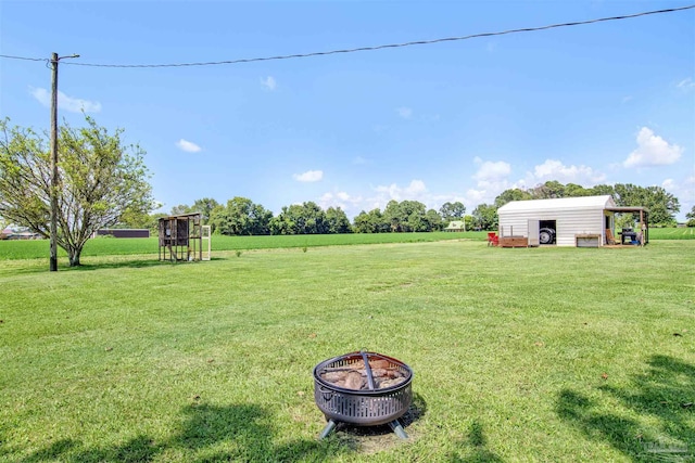 view of yard with an outdoor structure and an outdoor fire pit