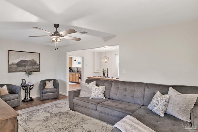 living room with hardwood / wood-style flooring, sink, and ceiling fan with notable chandelier