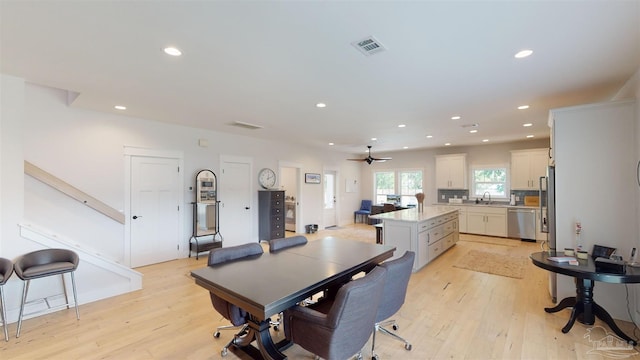 dining area with light hardwood / wood-style flooring, ceiling fan, and sink