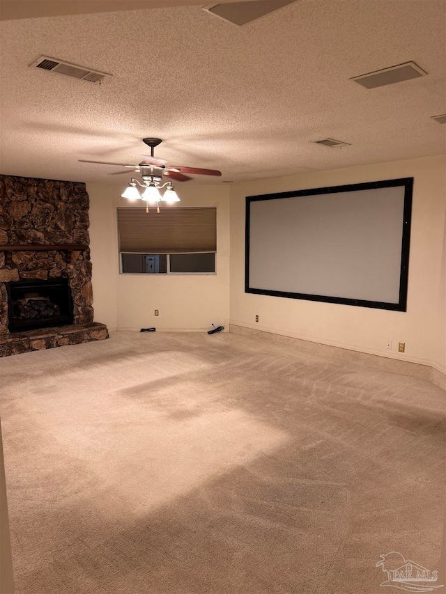 carpeted cinema featuring ceiling fan, a fireplace, and a textured ceiling