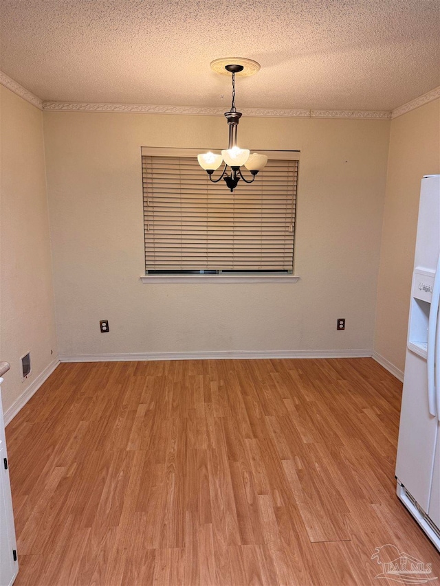 empty room with a textured ceiling, light wood-type flooring, and a chandelier