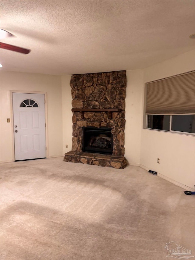 unfurnished living room with a textured ceiling, a fireplace, carpet flooring, and ceiling fan