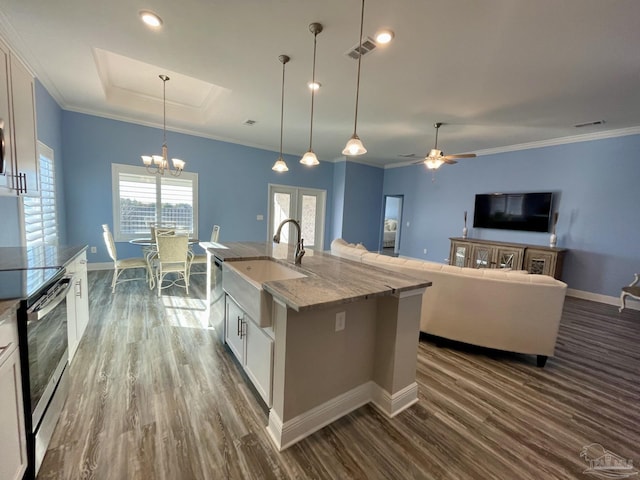 kitchen with light stone countertops, a center island with sink, white cabinets, ceiling fan with notable chandelier, and appliances with stainless steel finishes