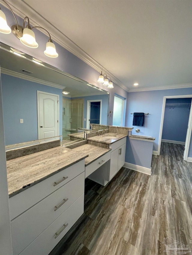 bathroom featuring vanity, wood-type flooring, ornamental molding, and walk in shower