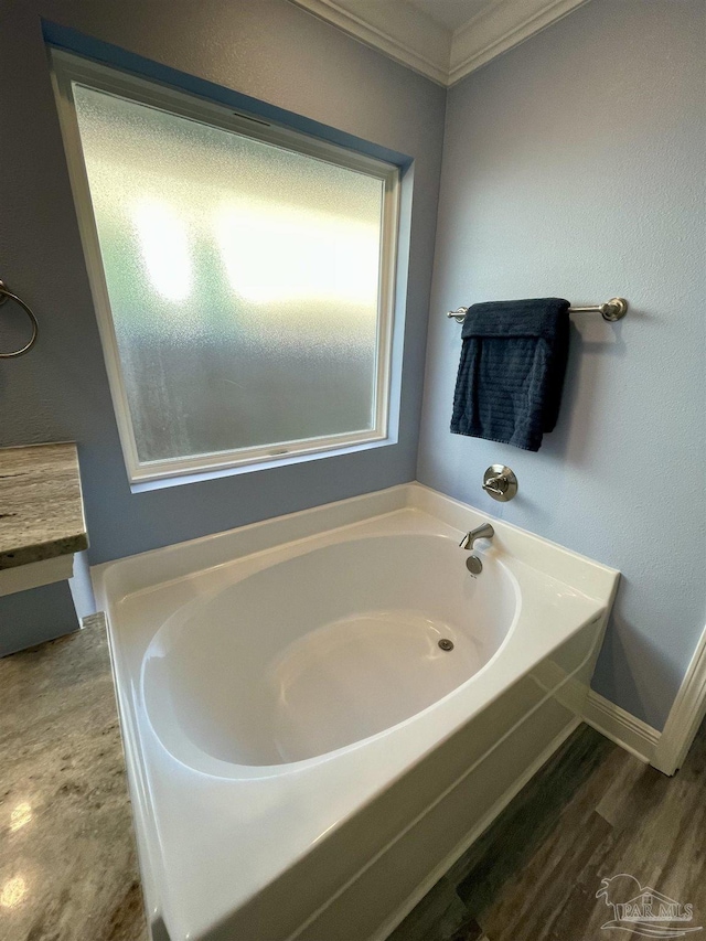 bathroom with ornamental molding, a bathing tub, and wood-type flooring