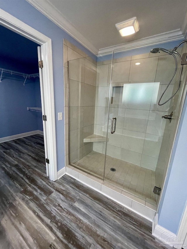 bathroom with hardwood / wood-style floors, a shower with door, and crown molding