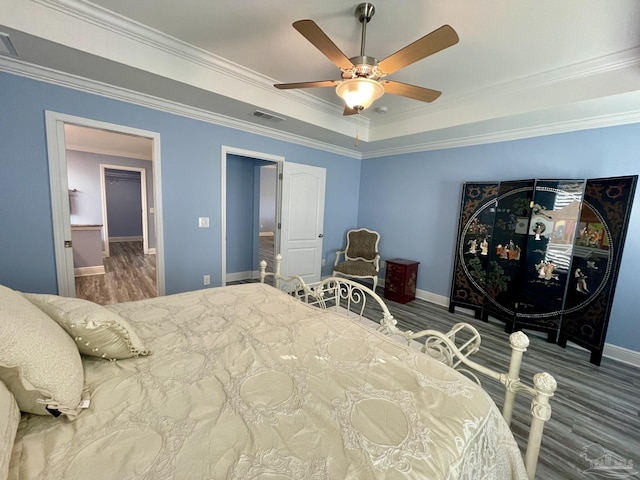 bedroom with a tray ceiling, ceiling fan, crown molding, and hardwood / wood-style flooring