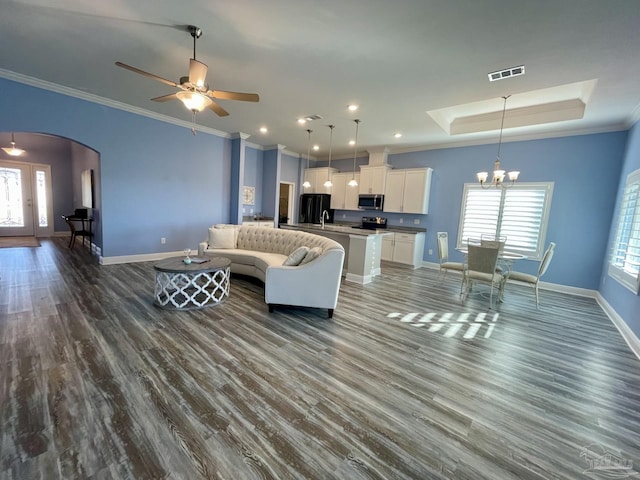 living room featuring plenty of natural light, dark hardwood / wood-style flooring, crown molding, and a tray ceiling