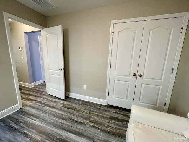 unfurnished bedroom with dark hardwood / wood-style flooring and a closet