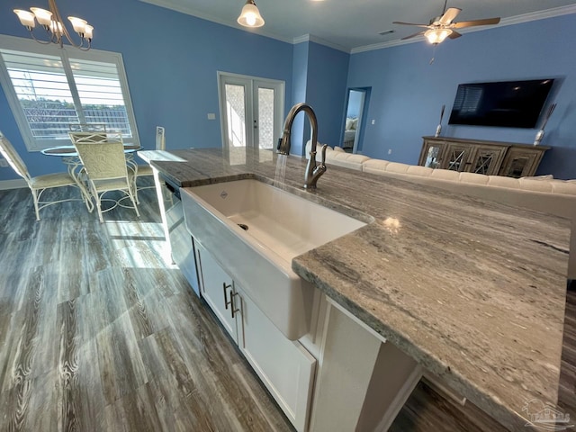 kitchen with light stone countertops, a wealth of natural light, hanging light fixtures, and sink