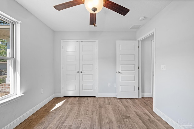 unfurnished bedroom with a closet, multiple windows, ceiling fan, and light hardwood / wood-style flooring