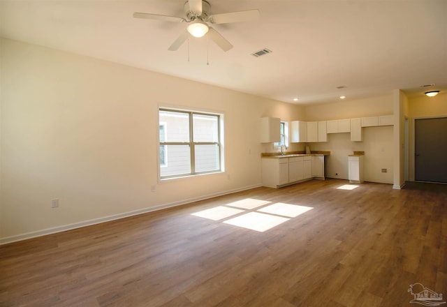 unfurnished living room featuring sink, ceiling fan, and wood-type flooring