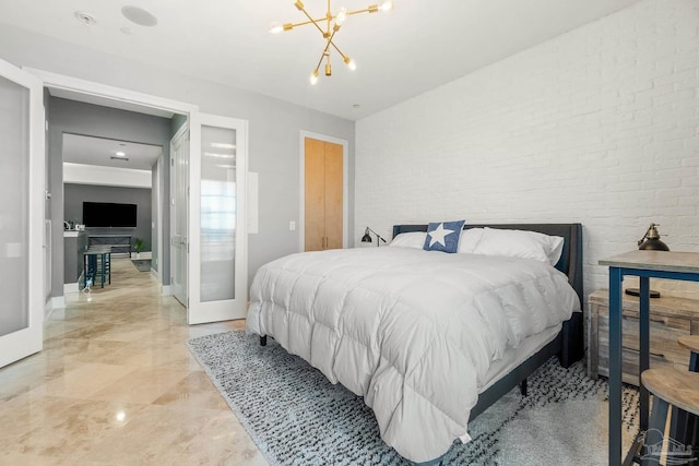 bedroom featuring brick wall, a notable chandelier, and french doors