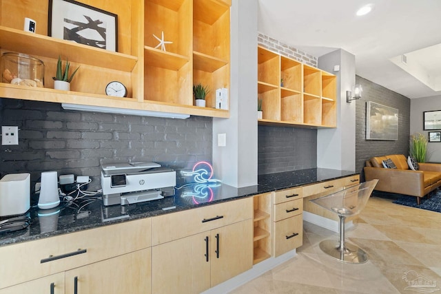 kitchen featuring tasteful backsplash, dark stone counters, and light brown cabinets