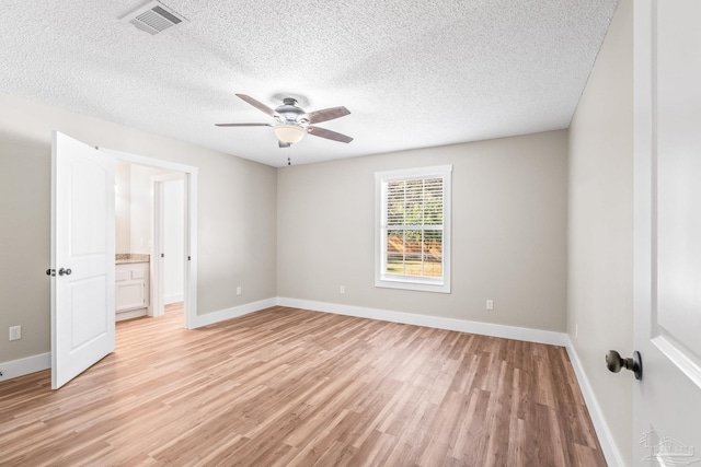 unfurnished bedroom with ceiling fan, light wood-type flooring, a textured ceiling, and ensuite bath