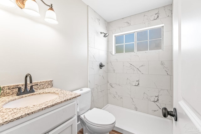 bathroom featuring vanity, toilet, and tiled shower