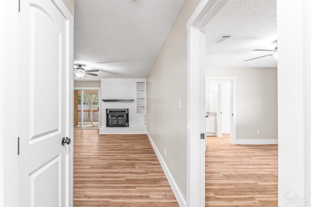 hall featuring a textured ceiling and light hardwood / wood-style flooring