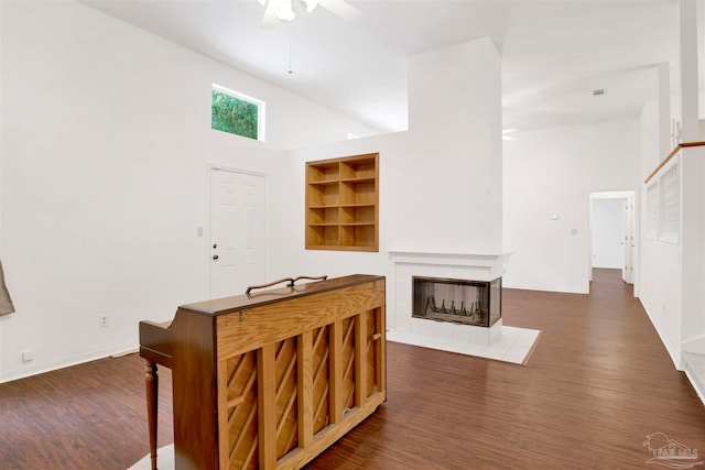 interior space featuring ceiling fan, dark hardwood / wood-style flooring, high vaulted ceiling, and a tile fireplace