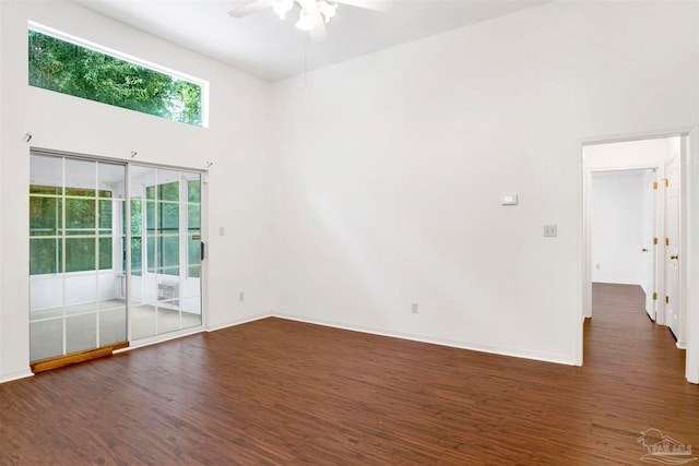 spare room featuring a towering ceiling, dark wood-type flooring, and ceiling fan