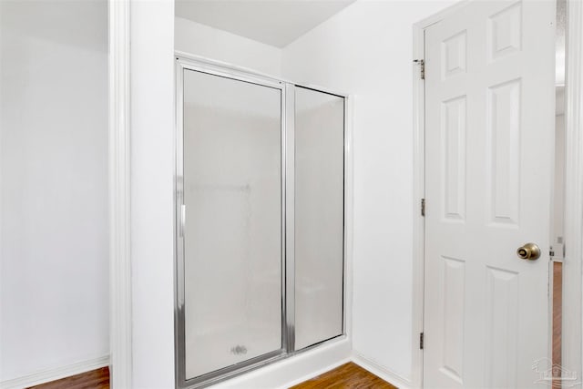 bathroom featuring wood-type flooring and an enclosed shower