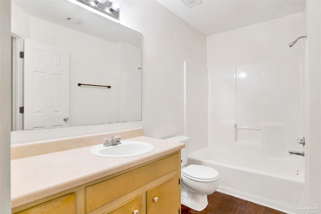 full bathroom with a textured ceiling, washtub / shower combination, hardwood / wood-style floors, vanity, and toilet