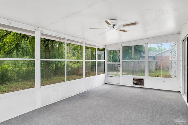 unfurnished sunroom with heating unit, ceiling fan, and a wealth of natural light