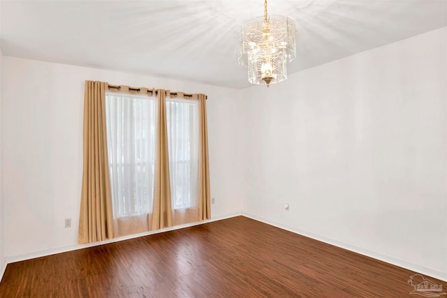 empty room featuring a chandelier and hardwood / wood-style flooring