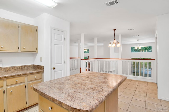 kitchen featuring ceiling fan with notable chandelier, decorative light fixtures, light tile patterned floors, and a center island