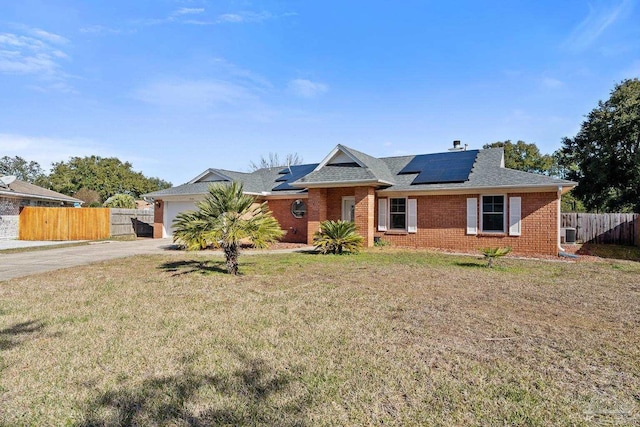 ranch-style home with a front yard, a garage, and solar panels