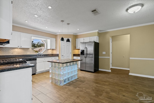 kitchen featuring pendant lighting, appliances with stainless steel finishes, a textured ceiling, a kitchen island, and white cabinetry