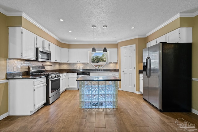 kitchen featuring a textured ceiling, white cabinets, stainless steel appliances, tasteful backsplash, and crown molding