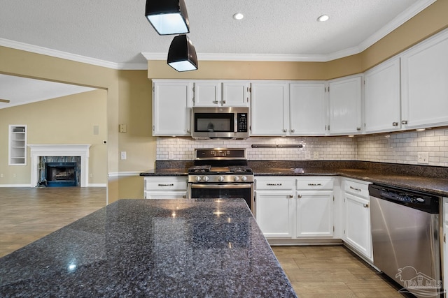 kitchen with white cabinets, a textured ceiling, appliances with stainless steel finishes, and dark stone countertops